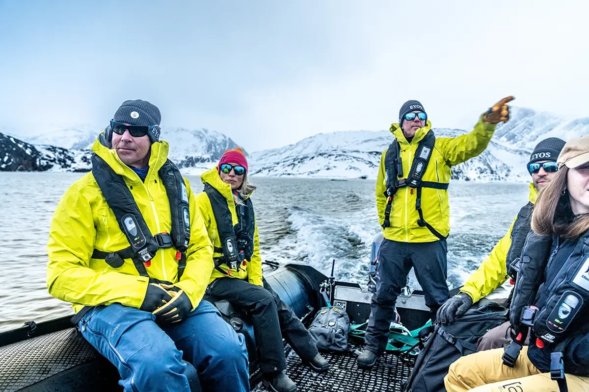 a group of man going down a river in a boat in greenland