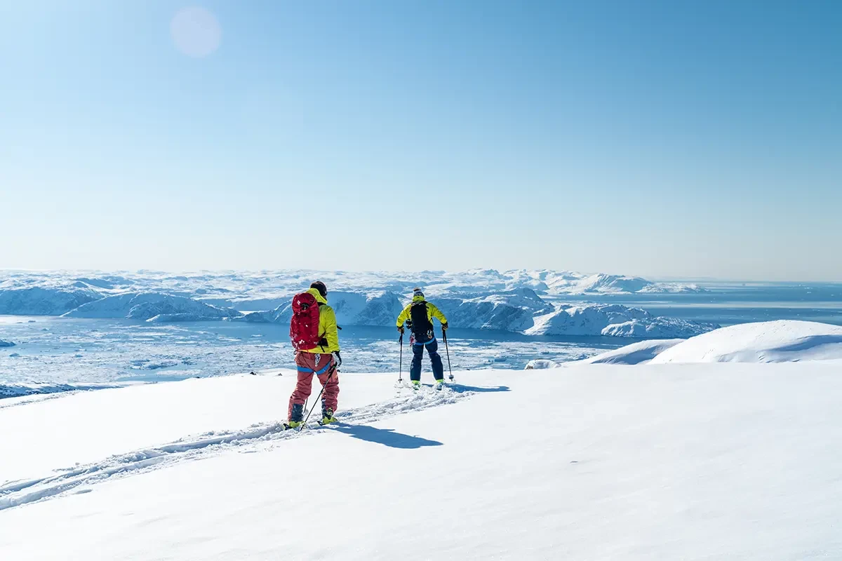 a pair of people walking in greenland on mountain