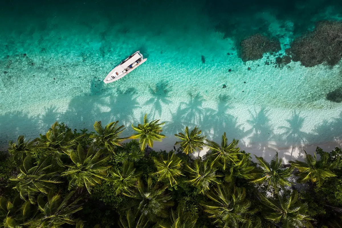 an birdseye view of a beach in indonesia with a boat docked on shore