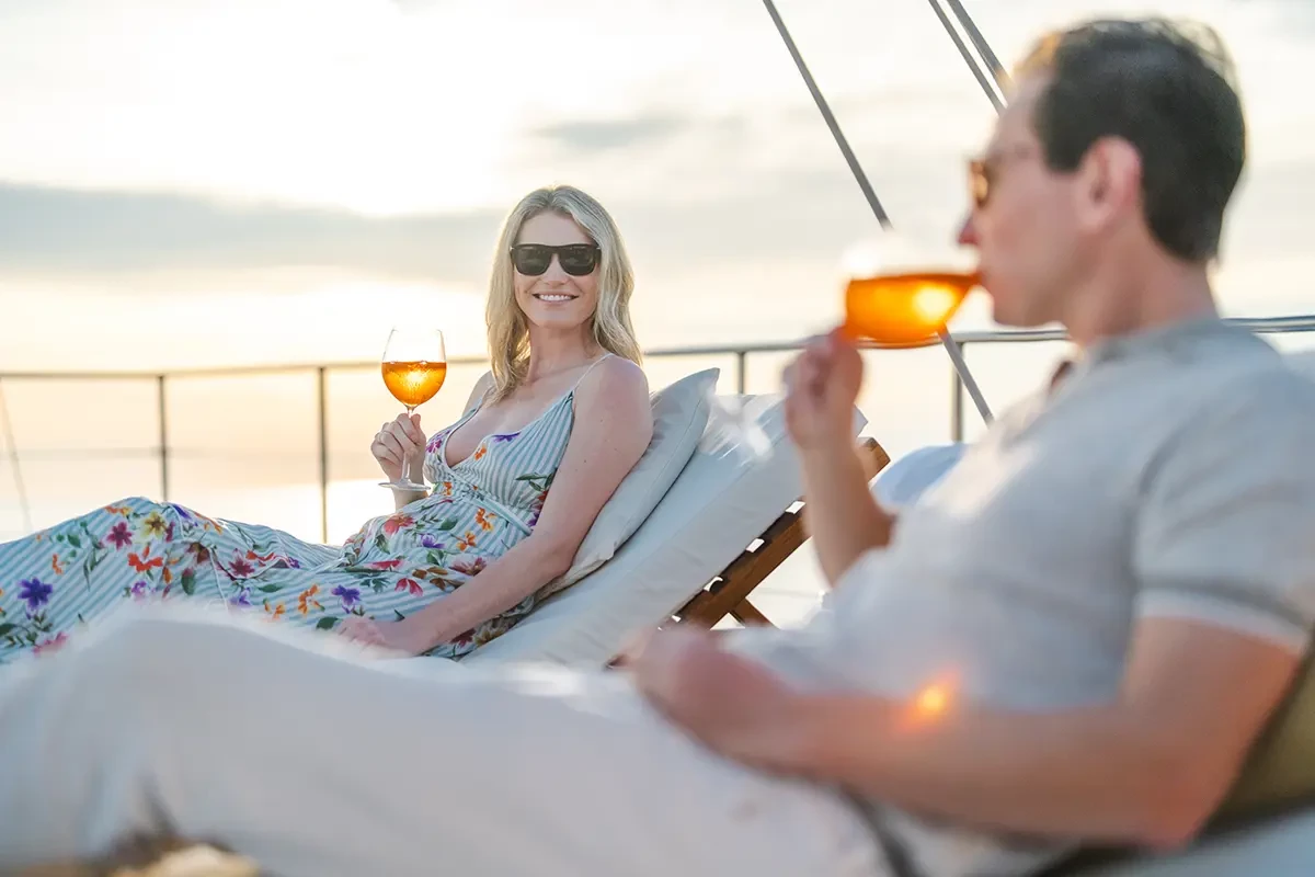 a couple enjoying some wine onboard a boat at sunset in indonesia