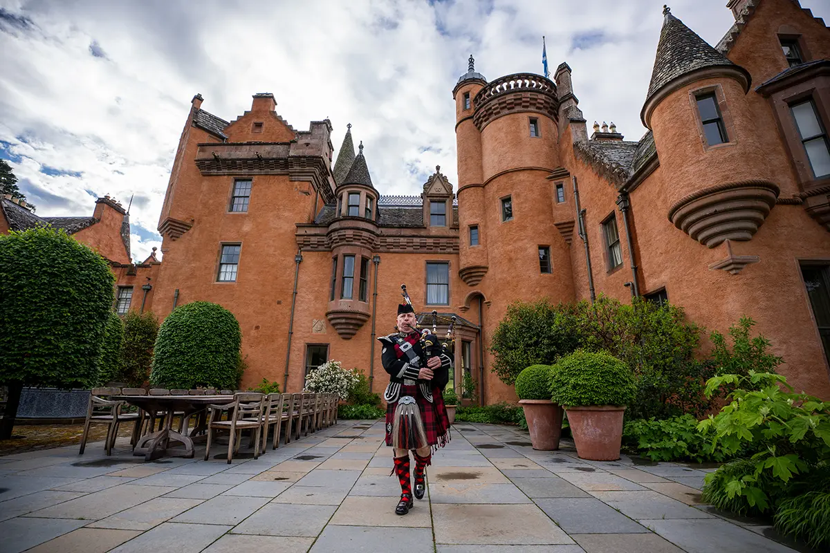 a bagpipe musician playing in front of a castle