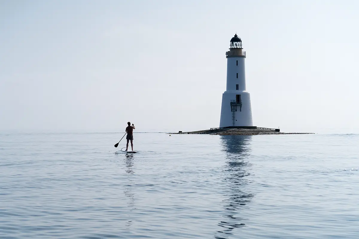 a surfer sailing in front of a lighthouse